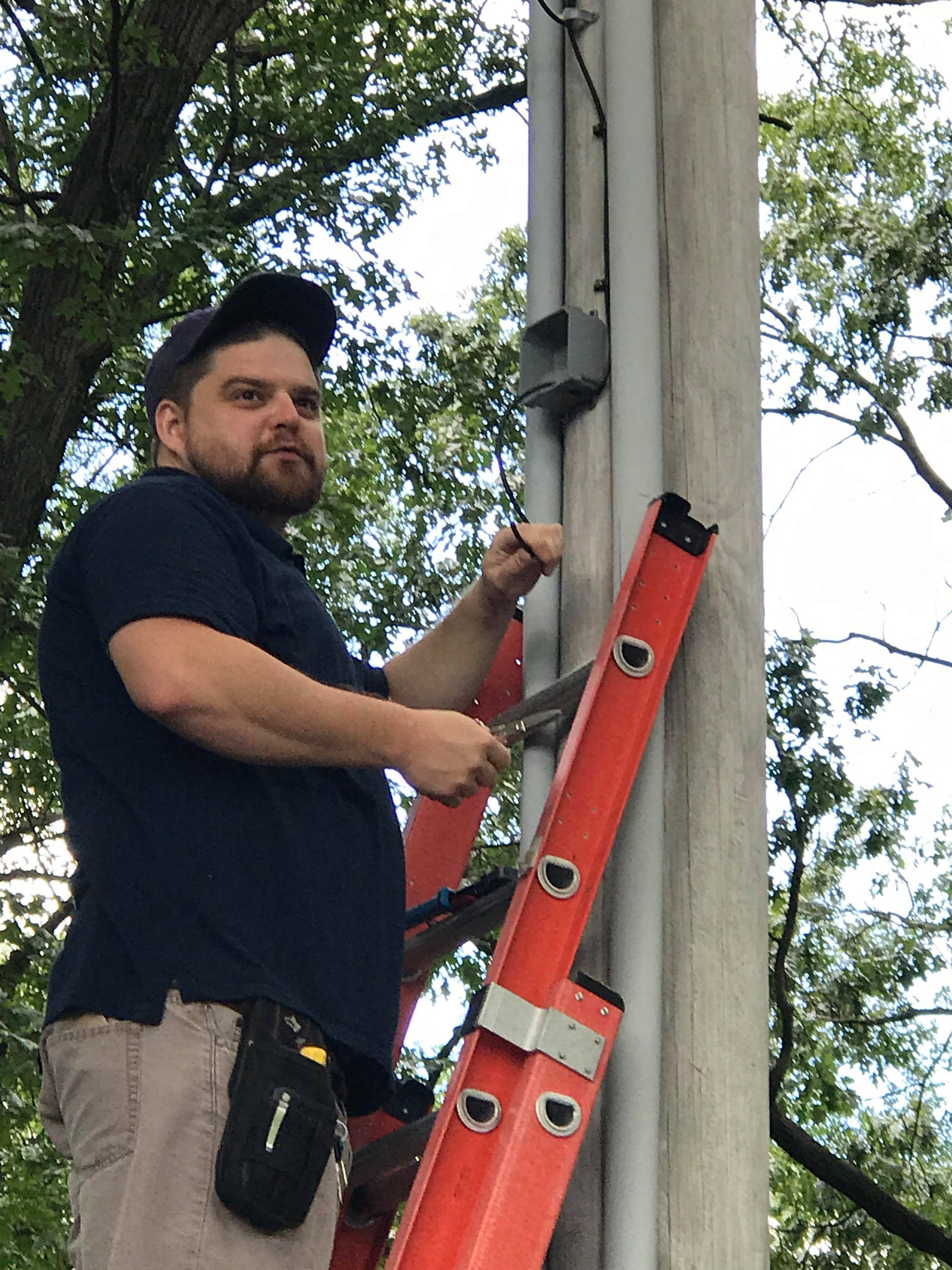 Valley Communications LLC technician on ladder performing outdoor installation