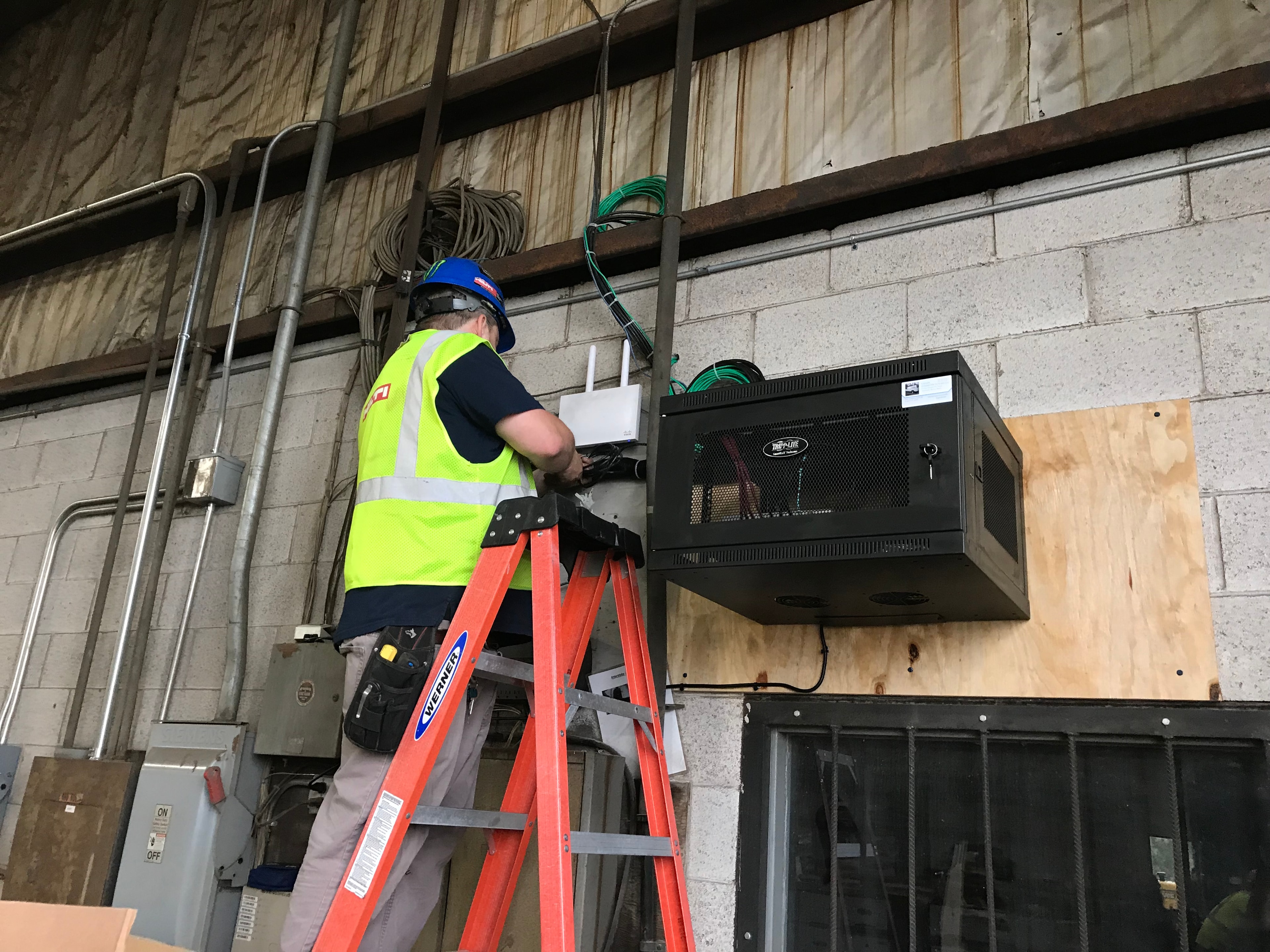 Technician in safety vest installing network cabinet in warehouse